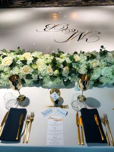 the table is set with silverware and white flowers