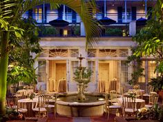 an outdoor dining area with tables and chairs in front of a large building at night