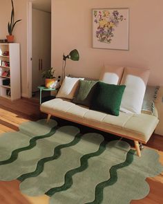 a living room with a couch, rug and bookshelf on the floor in front of it