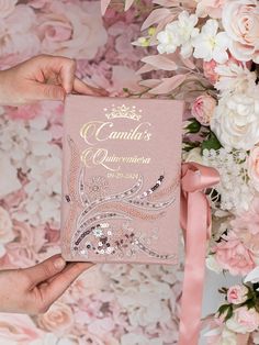 a person holding up a pink book in front of flowers