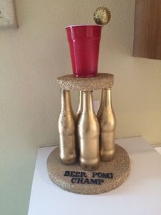 three beer bottles stacked on top of each other with a red cup in the middle