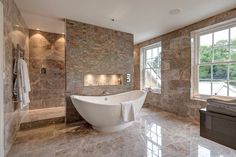 a large white bath tub sitting in a bathroom next to a window with lots of windows