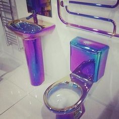 a toilet and sink in a bathroom with chrome fixtures on the wall, along with mirrors