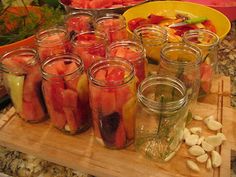 several jars filled with pickles and vegetables on a cutting board next to other food items