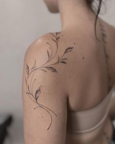 the back of a woman's shoulder with tattoos on it