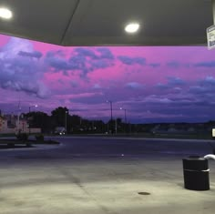 an empty gas station with purple clouds in the sky