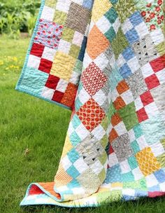 a colorful quilt is on the grass outside