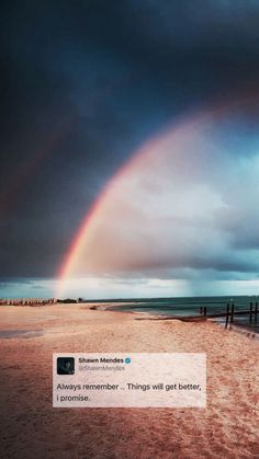 a rainbow appears in the sky over a beach