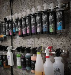 several bottles are lined up on the wall next to each other, with sprayers hanging above them