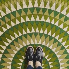 a person standing in front of a green and white floor with an intricate design on it