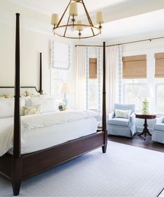 a bedroom with four poster bed and blue chairs