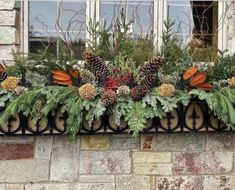 a window sill decorated with pine cones, evergreens and other greenery in front of a brick building