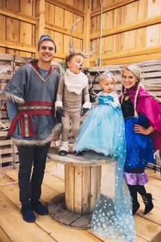 two adults and one child are posing for a photo in costumes on a wooden platform