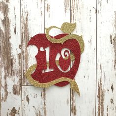 an apple cut out with the number ten on it, sitting against a white wooden background