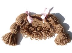 a crocheted hat with pink bows on it and tassels hanging from the side