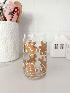 a clear glass with gingerbreads on it sitting on a counter next to a brush holder