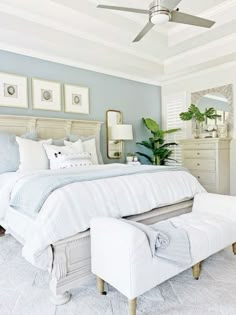 a white bed sitting in a bedroom under a ceiling fan