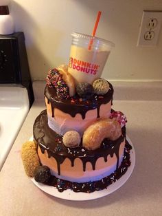 a triple layer cake with donuts on top and a cup of dunkin'donuts