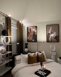 a bed with white sheets and pillows in a bedroom next to two pictures on the wall