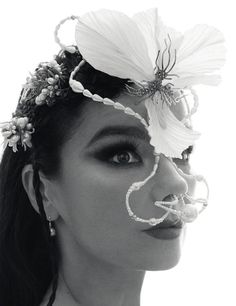 a woman with flowers on her head and nose is wearing a flower in her mouth