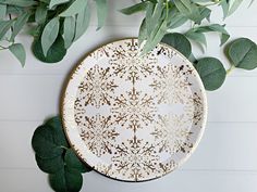 a white and gold plate surrounded by green leaves