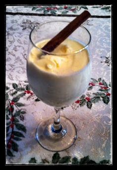 a glass filled with pudding sitting on top of a table next to a cinnamon stick