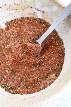 a white bowl filled with spices and a spoon