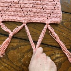 someone is knitting a pink crocheted hat with tassels on the side