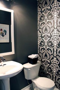 a white toilet sitting next to a sink in a bathroom under a framed painting on the wall