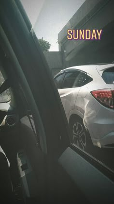 the back window of a car that is parked in front of a building with a sign reading sunday