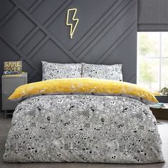 a bed with yellow and black comforters in a bedroom area next to a gray wall