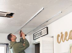 a man holding a bottle up to the ceiling in front of a sign that reads cottons