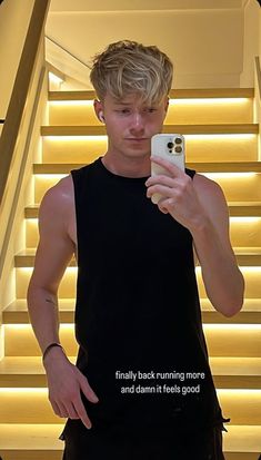 a young man taking a selfie with his cell phone in front of some stairs