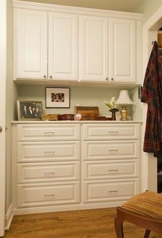 a white closet with many drawers and pictures on the wall