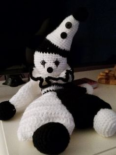 a crocheted stuffed animal wearing a black and white striped hat sitting on top of a table