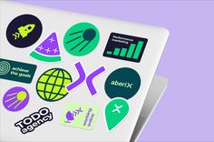 various stickers are displayed on the back of a white laptop computer with purple and green background