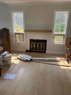 a living room with hard wood flooring next to two windows and a fire place