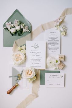 the wedding stationery is laid out with flowers and ribbon