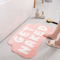 a woman is standing on the floor next to a bath mat that says get up and go