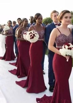 a group of people standing next to each other in long dresses and holding bouquets