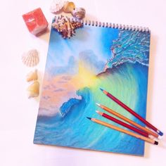 an artist's notebook with pencils and seashells next to it