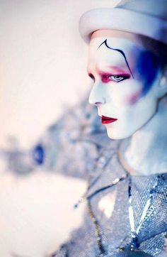 a mannequin with blue and white makeup is wearing a silver dress, hat and necklace