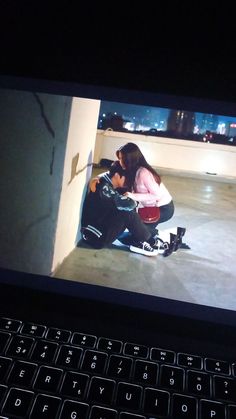 a woman sitting on the ground with her feet up next to a laptop computer screen