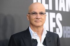 balding man in black suit and white shirt posing for the camera at an event