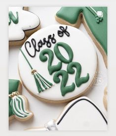 cookies decorated with green and white icing are arranged on a table, including one cookie that says class of 2012