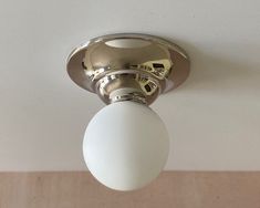 a ceiling light with a white ball hanging from it's center point on the ceiling