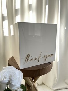 a white box with the word mom of pop written on it next to some flowers