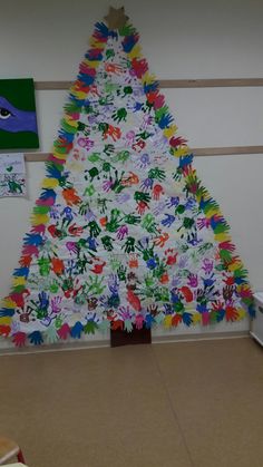 a christmas tree made out of handprints in a room with pictures on the wall