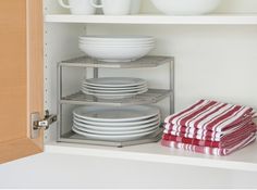 plates and bowls are stacked on the shelves in this kitchen cabinet, which is open to reveal dishes