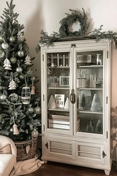 a christmas tree is next to a white china cabinet